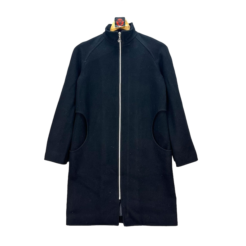 Peut inclure: Un manteau en laine noir avec un col montant et une fermeture &eacute;clair sur toute la longueur. Le manteau a deux grandes poches arrondies et des manches longues. Le manteau est de couleur noire unie et est pr&eacute;sent&eacute; sur fond blanc.
