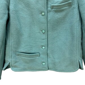 May include: A teal blue blazer with a button-up front and two pockets. The blazer is made of a soft, textured fabric.
