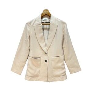 May include: A beige blazer with a notched lapel, two front pockets, and a single-button closure. The blazer is hanging on a wooden hanger. The brand name "snidel" is visible on the label.