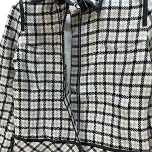 May include: A black and white checked jacket with a zip fastening. The jacket has a collar and black trim around the edges.