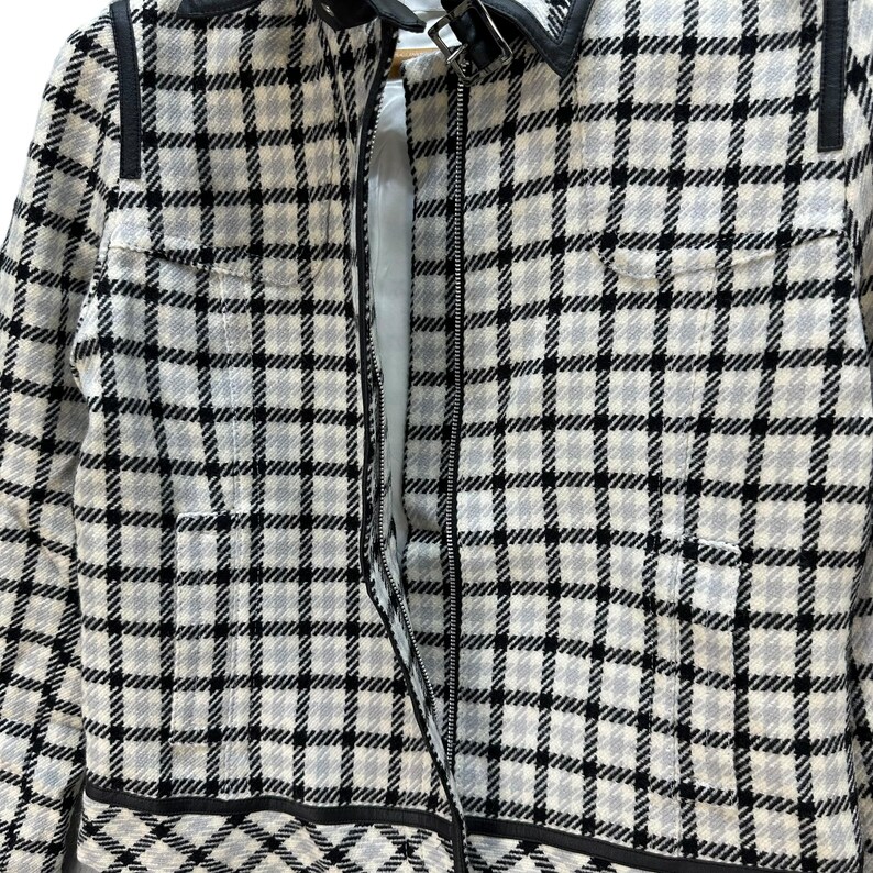 May include: A black and white checked jacket with a zip fastening. The jacket has a collar and black trim around the edges.