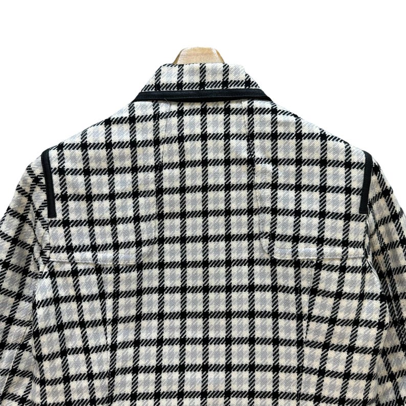 May include: A white and black checked jacket with black trim around the collar and shoulders.