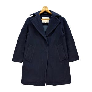 May include: A navy blue corduroy coat with a classic collar and two front pockets. The coat is hanging on a wooden hanger. The coat has a single-button closure and a tailored fit. The coat is a mid-length style.