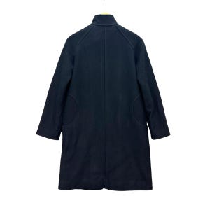 Peut inclure: Un manteau en laine noir avec un col montant et des manches longues. Le manteau a deux grandes poches arrondies et une coupe ajust&eacute;e. Il est suspendu &agrave; un cintre en bois sur fond blanc.