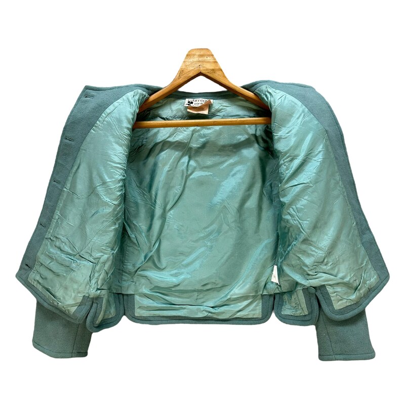 May include: A teal blue cropped jacket with a satin lining. The jacket has a button closure and long sleeves.