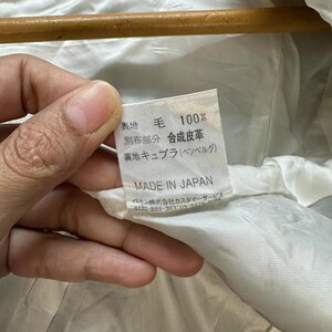 May include: A white fabric label with black text that reads "表地 毛 100% 別布部分 合成皮革 裏地 キュプラ(ベンベルグ) MADE IN JAPAN イトキン株式会社カスタマーサービス 0120-888-363:03-3478-808"