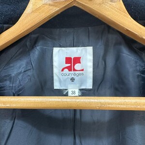 Peut inclure: Gros plan sur l'int&eacute;rieur d'un manteau fonc&eacute;. La doublure noire pr&eacute;sente une &eacute;tiquette blanche avec le nom de la marque "courr&egrave;ges" en texte noir et un logo rouge. La taille "38" est imprim&eacute;e sur l'&eacute;tiquette.
