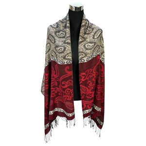 Könnte beinhalten: Gemusterter Schal mit Paisley-Design in Beige-, Burgunder- und Rottönen. Der Schal hat einen Fransenrand und ist über einer schwarzen Schaufensterpuppe drapiert. Das Design des Schals umfasst Blumen- und Paisley-Muster.
