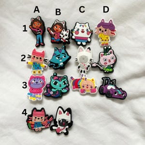 以下が含まれることがあります： カラフルな漫画のキャラクターの靴のチャームのセットです。チャームは、ピンクの髪の女の子、茶色の髪の女の子、猫、犬、ユニコーン、蝶など、さまざまなキャラクターを特徴としています。チャームはゴム製で、靴に取り付けるように設計されています。