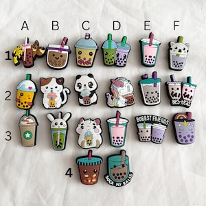 Peut inclure: Une collection de breloques de thé aux perles colorées avec divers motifs. Les breloques présentent différents animaux, boissons et textes, dont une licorne, un panda, un chat et la phrase "Suck My Balls."