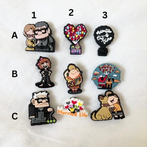 Peut inclure: Une collection de breloques de personnages de dessins animés colorés. Les breloques présentent des personnages et des éléments du film d'animation "Là-Haut", dont Carl, Ellie, Russell et la maison emblématique avec des ballons. Ces breloques sont idéales pour personnaliser des accessoires.