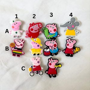 Puede incluir: Un conjunto de diez amuletos de zapatos de personajes de dibujos animados coloridos con Peppa Pig y su familia y amigos. Los amuletos están hechos de goma y tienen una variedad de diseños, incluyendo Peppa Pig como doctora, George Pig con una piruleta y Peppa Pig tocando la batería.