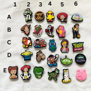 Puede incluir: Un conjunto de 24 abalorios para zapatos de personajes de dibujos animados coloridos que representan personajes de la franquicia Toy Story. Los abalorios incluyen a Woody, Buzz Lightyear, Jessie, el Sr. Cara de Papa, Rex, Slinky Dog y más.