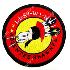 May include: A red, white, and yellow embroidered patch with the text "ABSENTEE SHAWNEE LI-SI-WI-NWI" and a Native American figure with feathers.