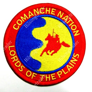 May include: Circular patch with a red border and the words "COMANCHE NATION LORDS OF THE PLAINS" in yellow. The center features a blue and yellow design with a red silhouette of a person on a horse.