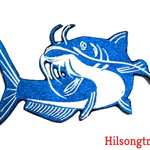 May include: Blue and white embroidered iron-on patch of a catfish with a detailed design.