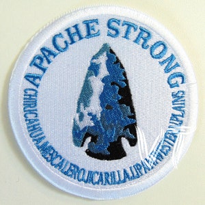 May include: White embroidered patch with a blue arrowhead in the center and the text "APACHE STRONG CHIRICAHUA MESCALERO JICARILLA APACHE WESTERN PLAINS" around the edge.