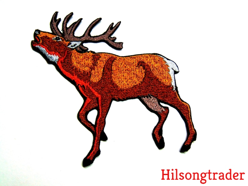 May include: Embroidered patch of a red deer with antlers, standing on all four legs with its head tilted back and mouth open, as if it is calling out. The deer is brown with a white patch on its rump.