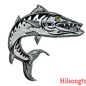May include: Embroidered patch featuring a stylized barracuda fish in shades of gray and black, with sharp teeth and a curved body. The patch has a white background and the text "Hilsongtrader" in red.