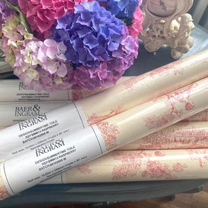 Può includere: Diversi rotoli di carta da parati Baer & Ingram Summertime Toile in color rosso lampone e crema. Ogni etichetta riporta il testo Design Summertime Toile, Ref SMRW13 Raspberry, e una dimensione del rotolo di 10,05 m x 520 mm o 11 iarde x 20 pollici.