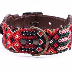 Puede incluir: Un collar de perro de cuero marrón con un patrón tejido rojo, verde, negro y blanco. El collar tiene una hebilla de latón y dos remaches de metal.