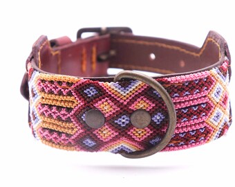 May include: A colorful dog collar with a geometric pattern in shades of pink, purple, orange, and brown. The collar is made of leather and has a metal buckle and D-ring.
