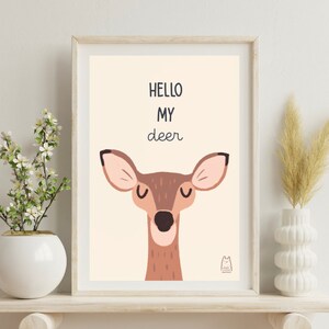 May include: A framed print with a light brown background featuring a cartoon deer with closed eyes and the text "HELLO MY deer".