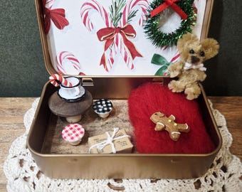 May include: A miniature Christmas-themed scene inside a gold tin. The tin contains a red heart with a gingerbread man, a teddy bear, and miniature items like a teacup, mushrooms, and a small gift box. The tin's interior features candy cane and bow designs.