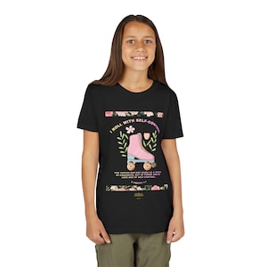 May include: Black t-shirt featuring a pink roller skate graphic with floral accents and the text "I ROLL WITH SELF-CONTROL." The design includes a Bible verse. The shirt is worn by a person.