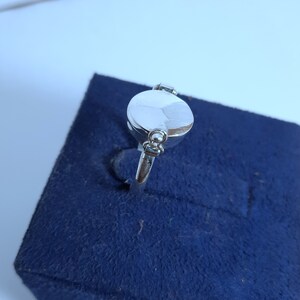 May include: A silver ring with a round, smooth top. The ring has a small, round detail on the side.