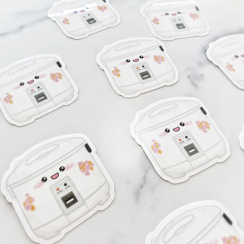 May include: A set of eight white rice cooker stickers with a cute cartoon face and pink flower accents. The stickers are perfect for adding a touch of whimsy to any kitchen.