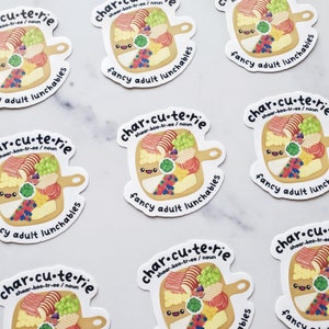 Pu&ograve; includere: Pi&ugrave; adesivi con un design di tagliere di salumi di cartone animato. Il tagliere &egrave; pieno di vari cibi, tra cui formaggio, cracker, uva e frutta. Il testo sull'adesivo recita "char.cu.te.rie shaar-koo-tr-ee/noun fancy adult lunchables".