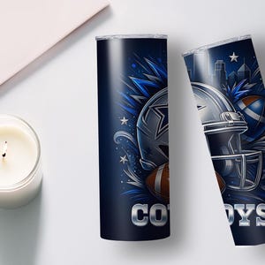 Pode incluir: Dois copos isolados azul marinho com tema de futebol americano. Um copo apresenta a palavra "COWBOYS" em prata, e o outro um capacete e bolas de futebol. O design inclui estrelas e um horizonte.