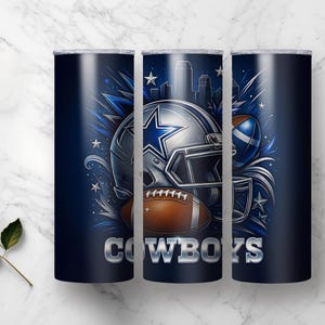 Pode incluir: Um copo azul marinho com um design de capacete de futebol, uma bola e a palavra "COWBOYS" em prata. O design inclui uma paisagem urbana e estrelas, perfeito para os f&atilde;s de desporto.