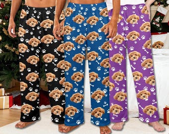 May include: Comfortable pajama trousers in black, blue, and purple, adorned with a repeating pattern of cute dog faces, white paw prints, and bones. Ideal for relaxing and sleeping.