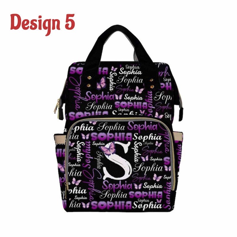 K&ouml;nnte beinhalten: Schwarze Wickeltasche mit einem lila und wei&szlig;en Schmetterlingsmuster und dem Namen "Sophia", der sich wiederholt. Die Tasche hat eine gro&szlig;e Fronttasche mit einem schwarzen "S" und einem Schmetterling.