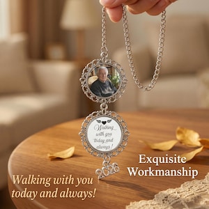 May include: A silver-toned memorial ornament with a photo of a person in a decorative frame, suspended from a chain. The ornament includes a second frame with the text "Walking with you today and always!" and the year "2026".