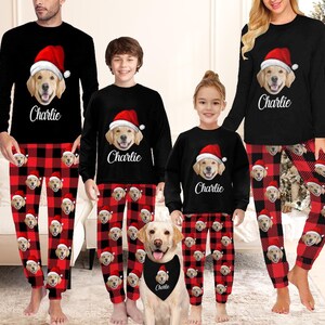 May include: Matching family Christmas pajamas. Black long-sleeve shirts with a golden retriever wearing a Santa hat and the name "Charlie". Red and black plaid pajama pants with golden retriever faces. A dog wears a matching bandana.