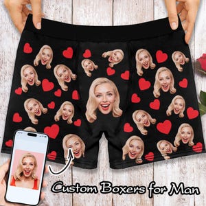 Może przedstawiać: Czarne bokserki z powtarzającym się wzorem czerwonych serc i twarzy osoby. Tekst "Custom Boxers for Man" znajduje się na dole obrazu.