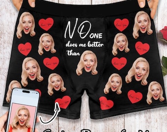 Könnte beinhalten: Schwarze Boxershorts mit einem sich wiederholenden Muster aus einem Frauen Gesicht und roten Herzen. Der Text "NO ONE does me better than" ist auf der Vorderseite der Boxershorts aufgedruckt.