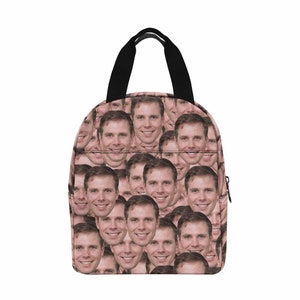 May include: A pink lunch bag with a black handle and zipper. The bag is covered in a repeating pattern of a man's face.