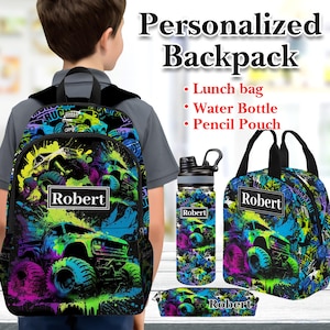 May include: A personalized backpack set featuring a backpack, water bottle, lunch bag, and pencil pouch. The set has a colorful monster truck design with the name "Robert" on each item. The design includes splashes of blue, green, and purple.