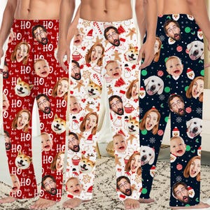 May include: Three pairs of pajama pants featuring custom photo prints of faces and pets. The first pair is red with 'HO HO HO' text, the second is white with gingerbread men and candy canes, and the third is navy blue with Christmas ornaments.