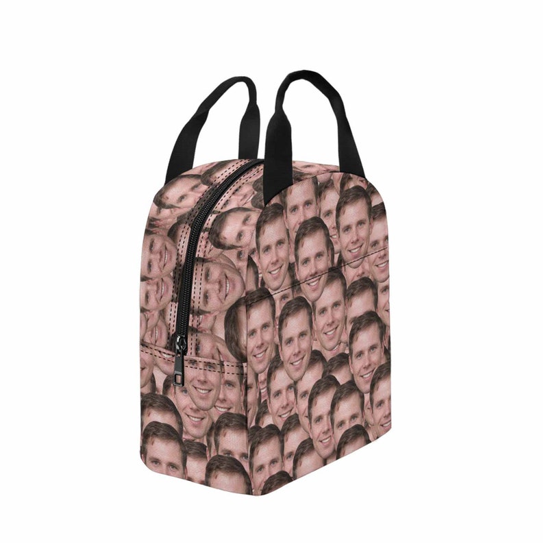 May include: A black lunch bag with a zipper closure and two handles. The bag is covered in a pattern of a man's face.