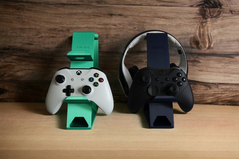 K&ouml;nnte beinhalten: Zwei Controller-St&auml;nder, einer gr&uuml;n und einer schwarz, mit Controllern darauf. Der gr&uuml;ne St&auml;nder hat den Text "IDBLADE" darauf. Der schwarze St&auml;nder hat den Text "Hyperkin" darauf.