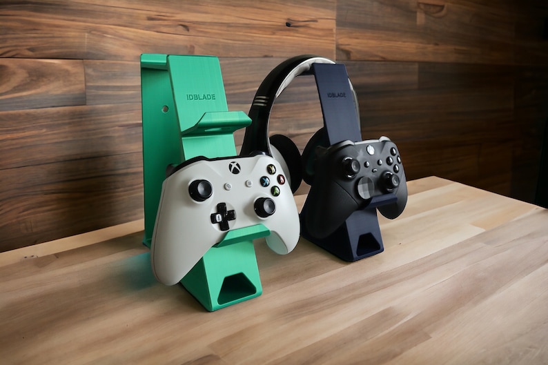 K&ouml;nnte beinhalten: Zwei Controller-St&auml;nder, einer gr&uuml;n und einer schwarz, mit Controllern und Kopfh&ouml;rern. Die St&auml;nder sind mit "IDBLADE" beschriftet.