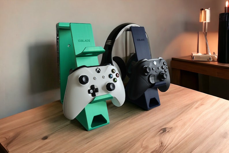 K&ouml;nnte beinhalten: Zwei gr&uuml;ne und schwarze Gaming-Controller-St&auml;nder mit einem wei&szlig;en und schwarzen Controller auf jedem St&auml;nder. Die St&auml;nder haben den Schriftzug "IDBLADE" aufgedruckt. Die St&auml;nder stehen auf einer Holzoberfl&auml;che.