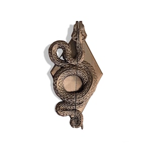 May include: A bronze snake door knocker with a diamond-shaped base. The snake is coiled and has a detailed texture.