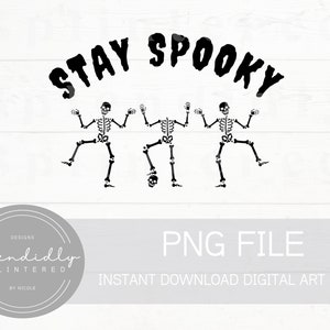 以下が含まれることがあります： 白い背景に、3体の黒い骸骨が「Stay Spooky」という文字の下で踊っている。