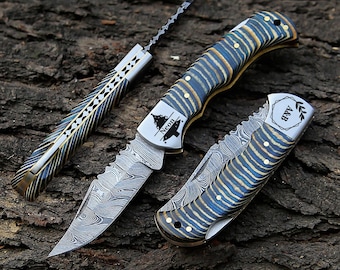 May include: Three custom knives with patterned blades and handles. One is a long, thin blade with a decorative handle. The other two are folding knives with blue and gold striped handles. One knife has the word "Neon" on the blade.